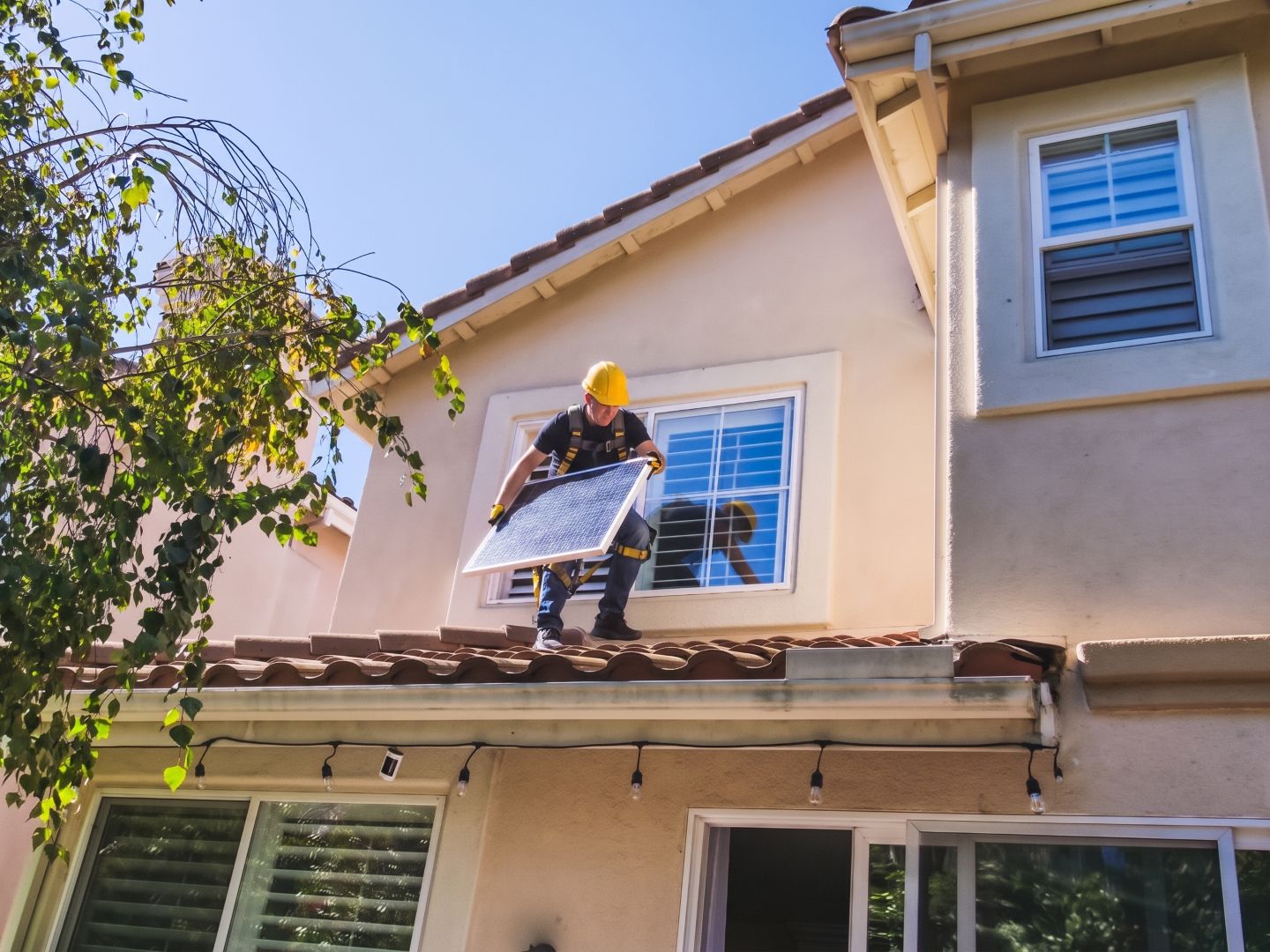 installatore con caschetto sul tetto con pannello fotovoltaico in mano